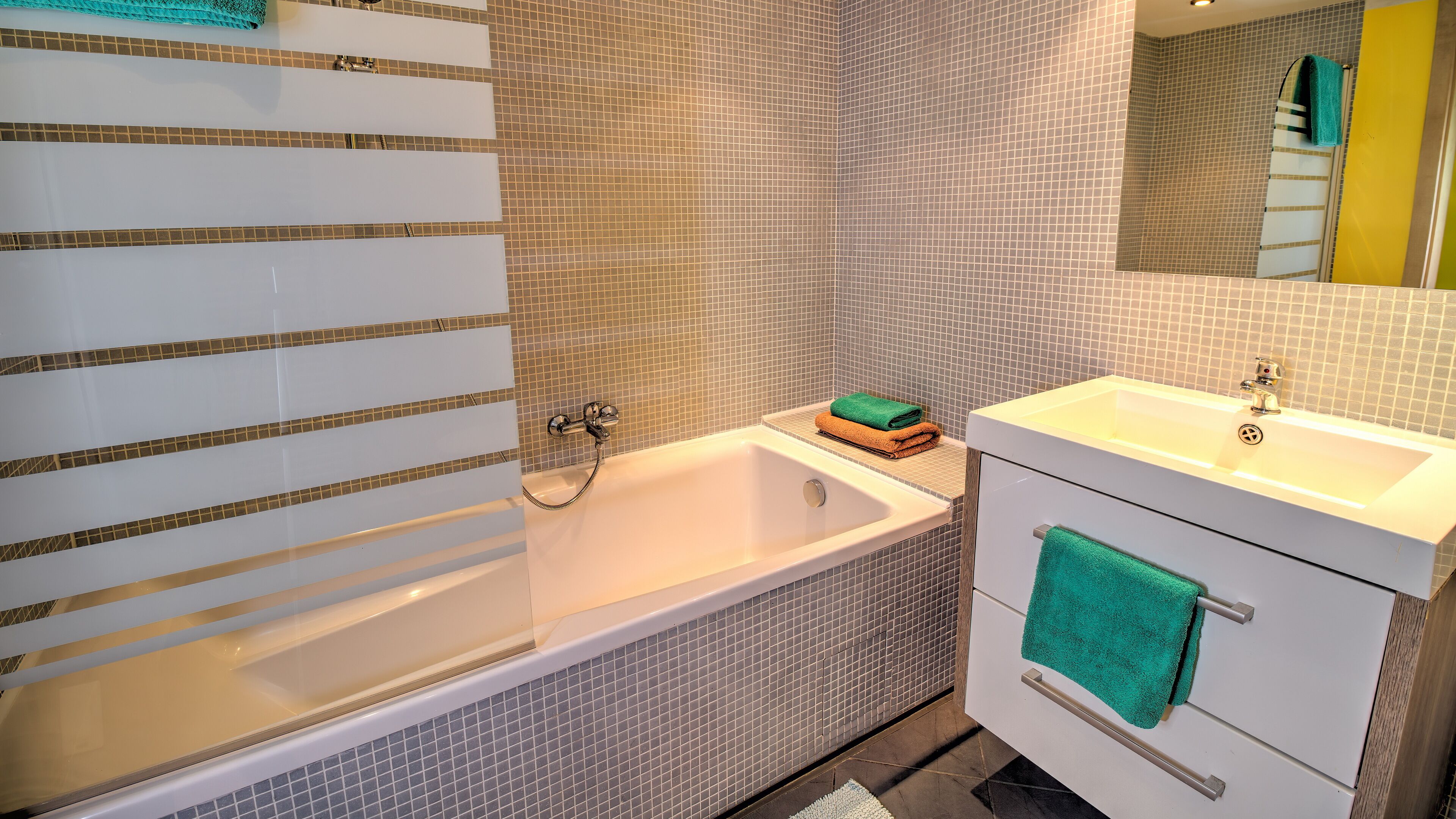 A bathroom with a bathtub, a sink, and a mirror.