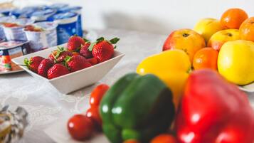 A table with a variety of fruits and vegetables, including strawberries, apples, oranges, and tomatoes.