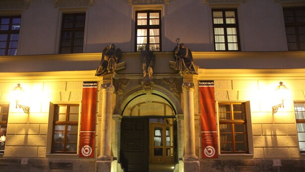 A building entrance with a grand archway, columns, and statues.