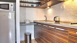 A modern kitchen with a microwave, kettle, and stainless steel sink.