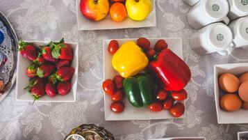 A table with various food items, including strawberries, tomatoes, bell peppers, and eggs.