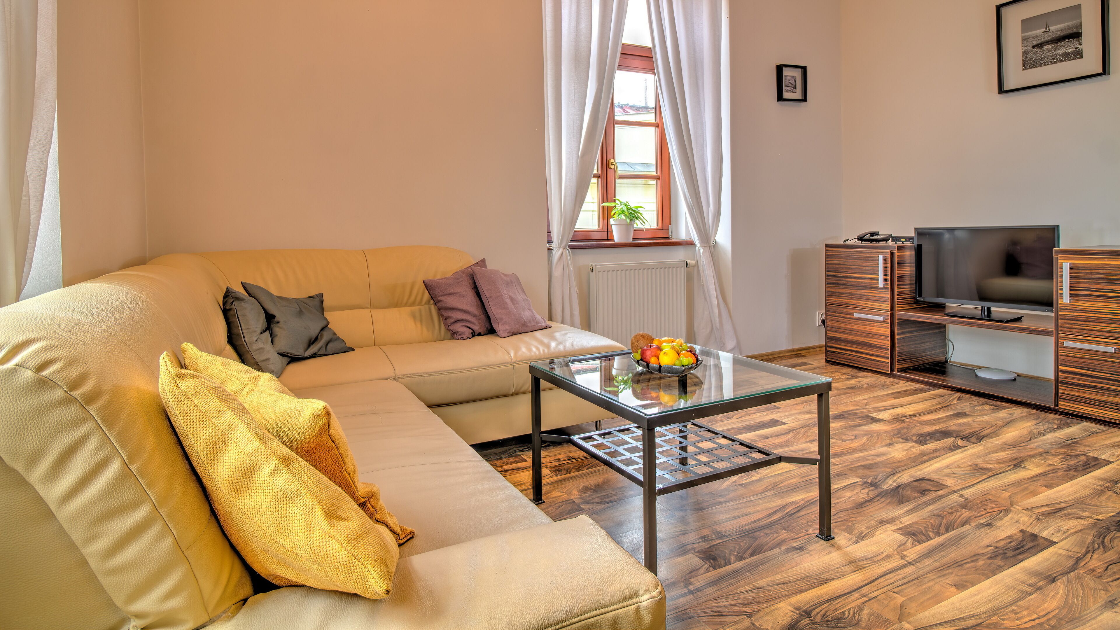 Una sala de estar con un sofá, una mesa de centro de vidrio, un televisor y un mueble de madera.