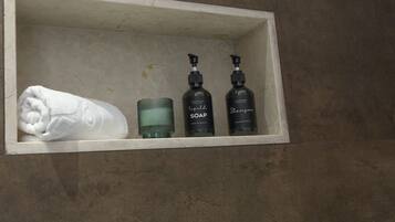 Ein Badezimmerschrank mit Handtuch, Seifenspender und Shampoo-Flasche.