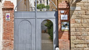 Una entrada con portón, un letrero que indica ‘prohibido estacionar’, un aviso de tarifa de entrada de 15 céntimos y un cartel de Bohemian que anuncia un negocio local.