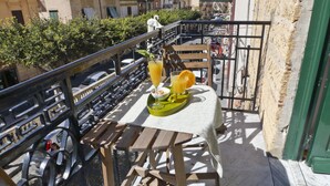 Un balcón con una mesa dispuesta para el desayuno, que incluye zumo de naranja y un bol de cereales.