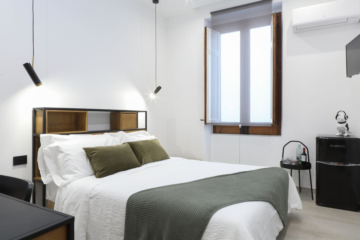 Un dormitorio ordenado con cama, mesita de noche y un pequeño escritorio.