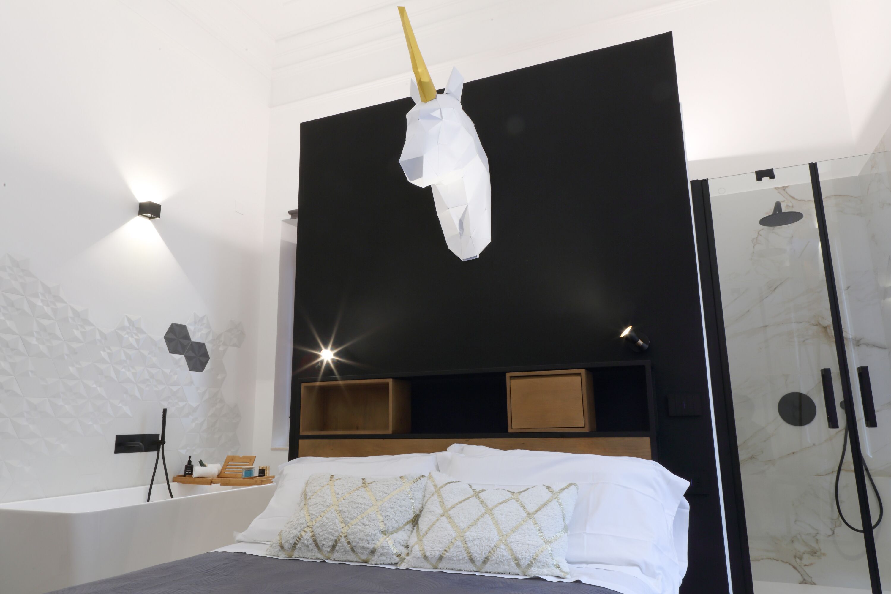 A modern bedroom with a bed, a headboard, a bedside table, and a shower area.