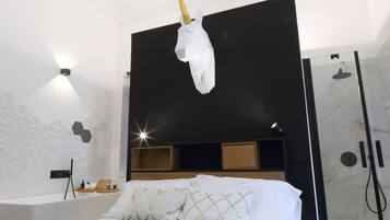 A modern bedroom with a bed, a headboard, a bedside table, and a shower area.