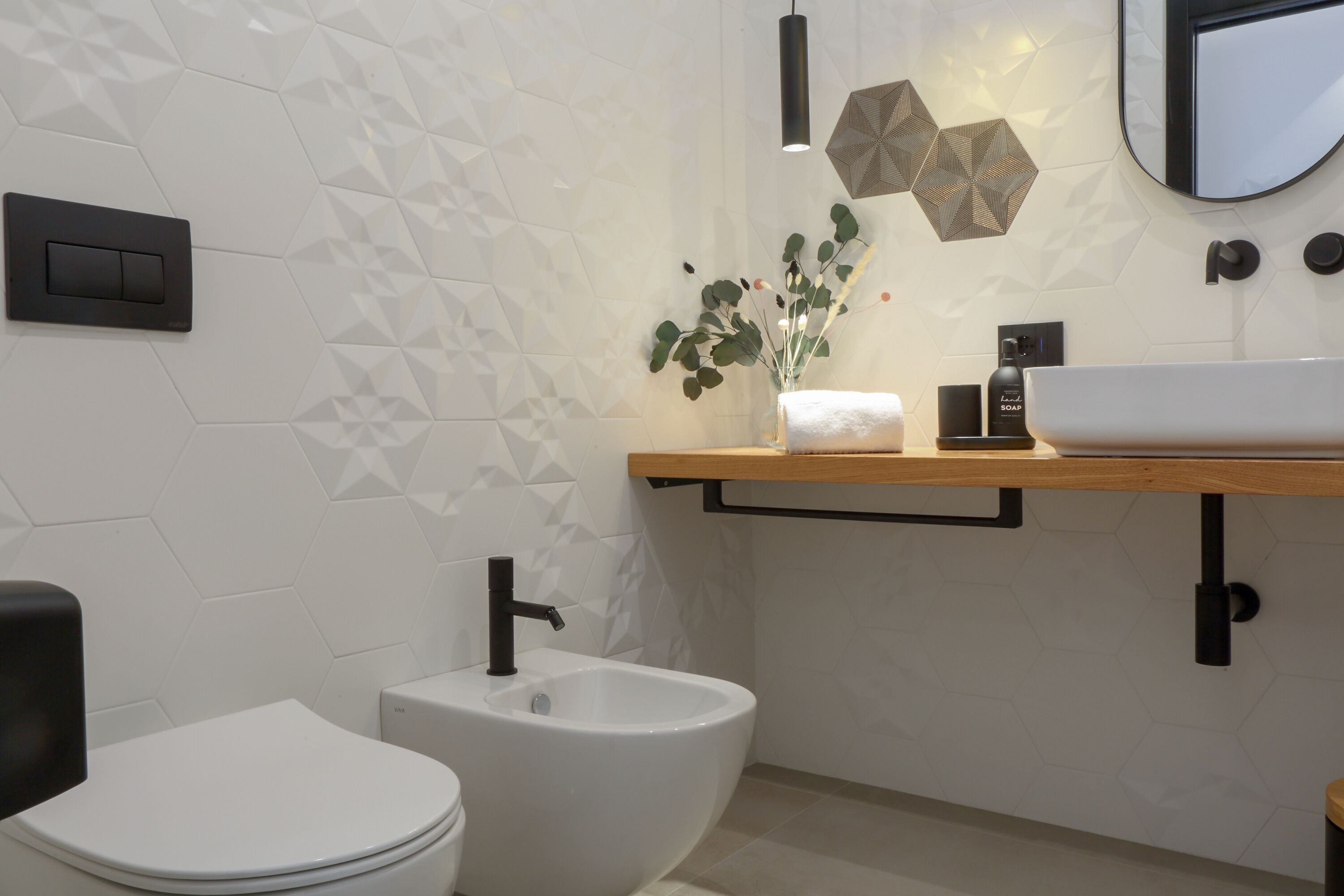 Un baño moderno con inodoro blanco, un bidé, un mueble de tocador de madera con lavabo y un espejo.