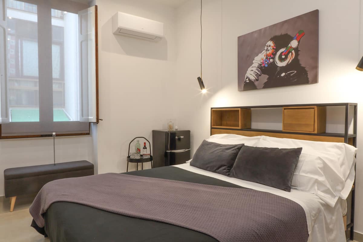 Un dormitorio moderno con cama, banco y obra de arte.