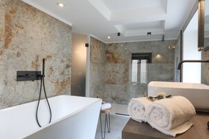 Un baño moderno con una bañera independiente, un espejo grande y un perchero para toallas.