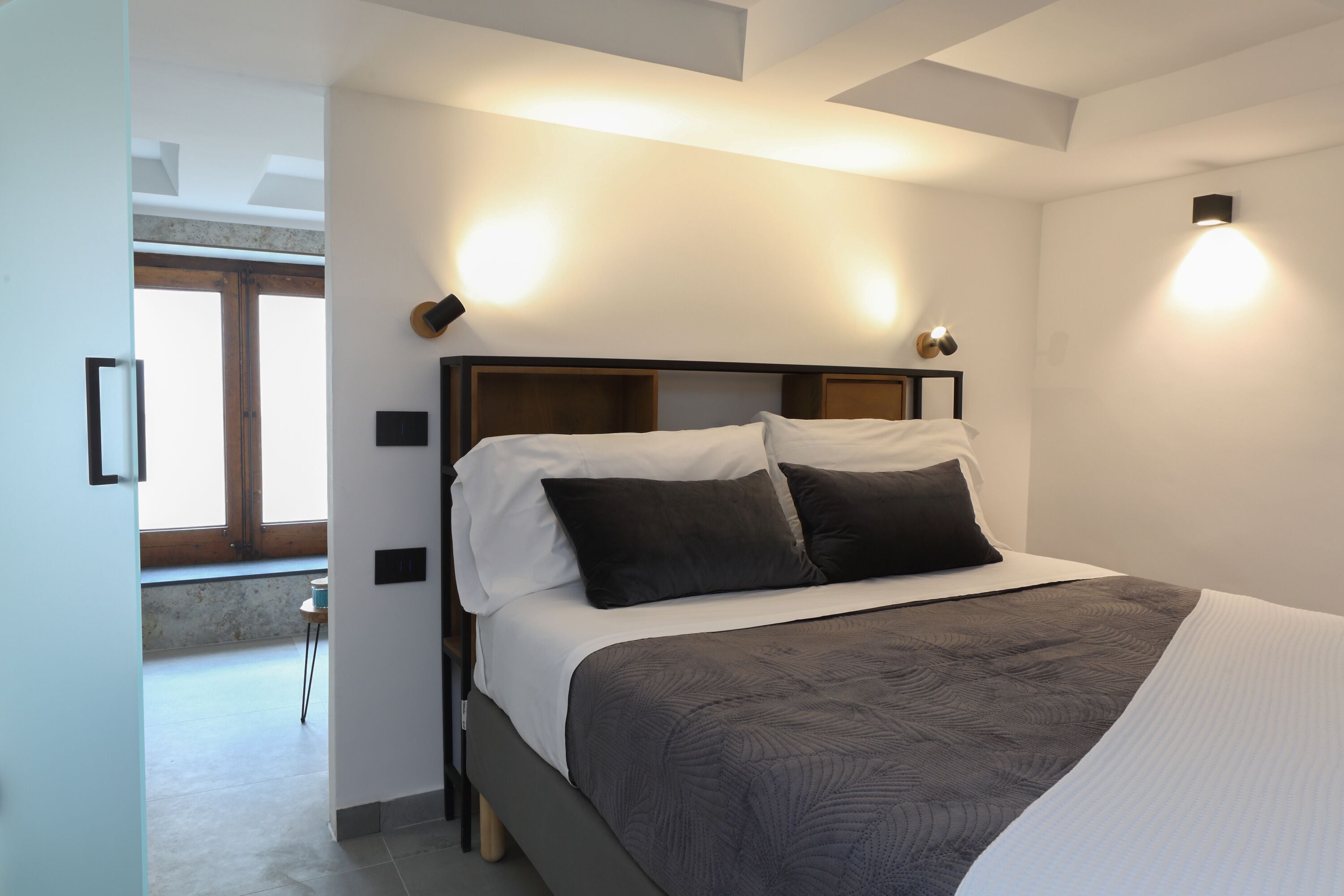 Un dormitorio moderno con una cama grande, dos mesitas de noche y un tragaluz.