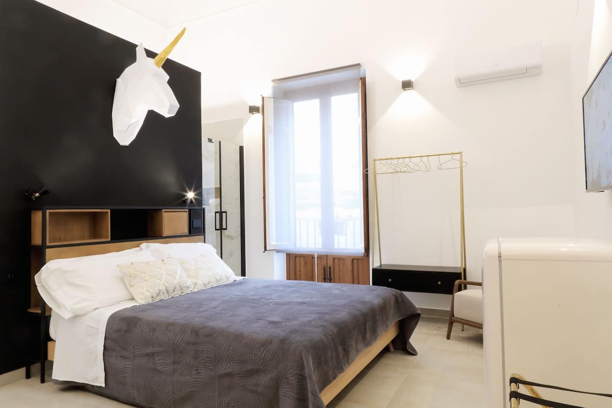 Un dormitorio moderno con cama, mesitas de noche, armario, espejo y ventana.