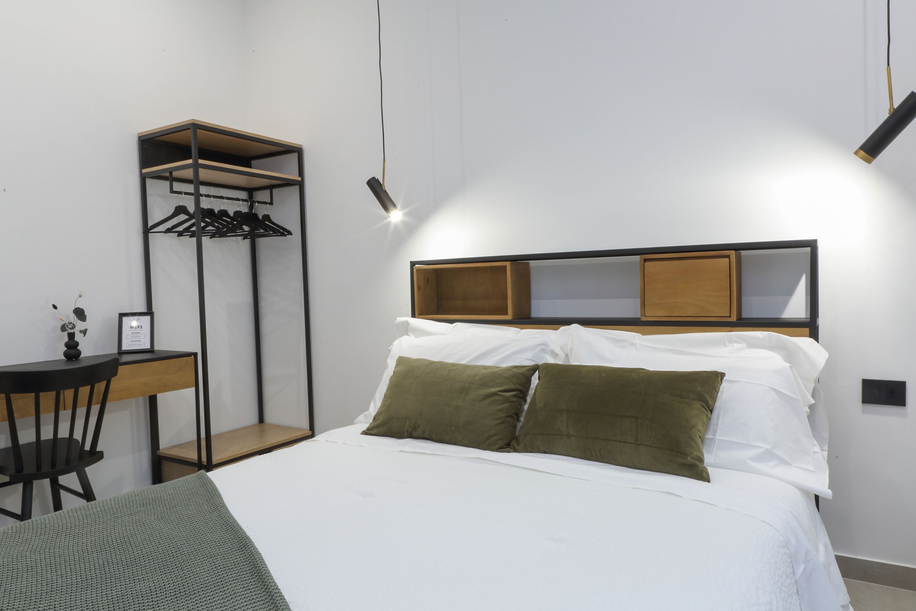 A neatly arranged bedroom with a bed, a desk, and a wardrobe.