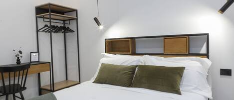 A neatly arranged bedroom with a bed, a desk, and a wardrobe.