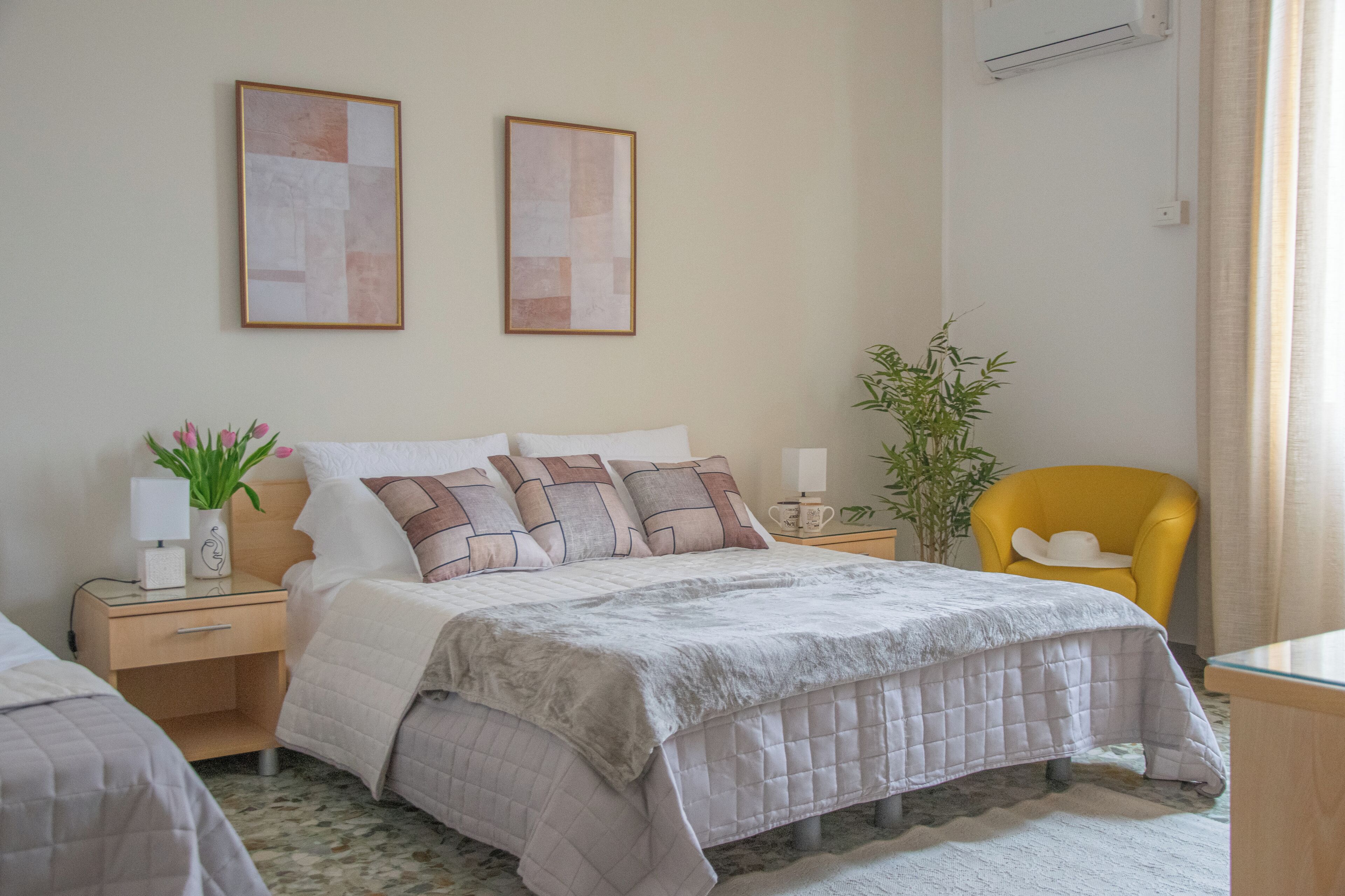 A bedroom with a bed, bedside tables, a chair, and wall art.
