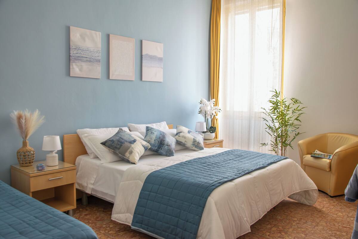 Ein Schlafzimmer mit einem Bett, Nachttischen, einem Sessel und Bildern an der Wand.