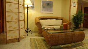 A room with a wicker sofa, a glass coffee table, a lamp, and a plant. - Farsund (Sanxenxo)
