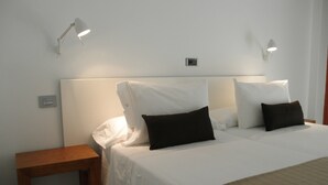 A hotel room with a bed, two bedside tables, and two wall-mounted lamps. - Farsund (Sanxenxo)