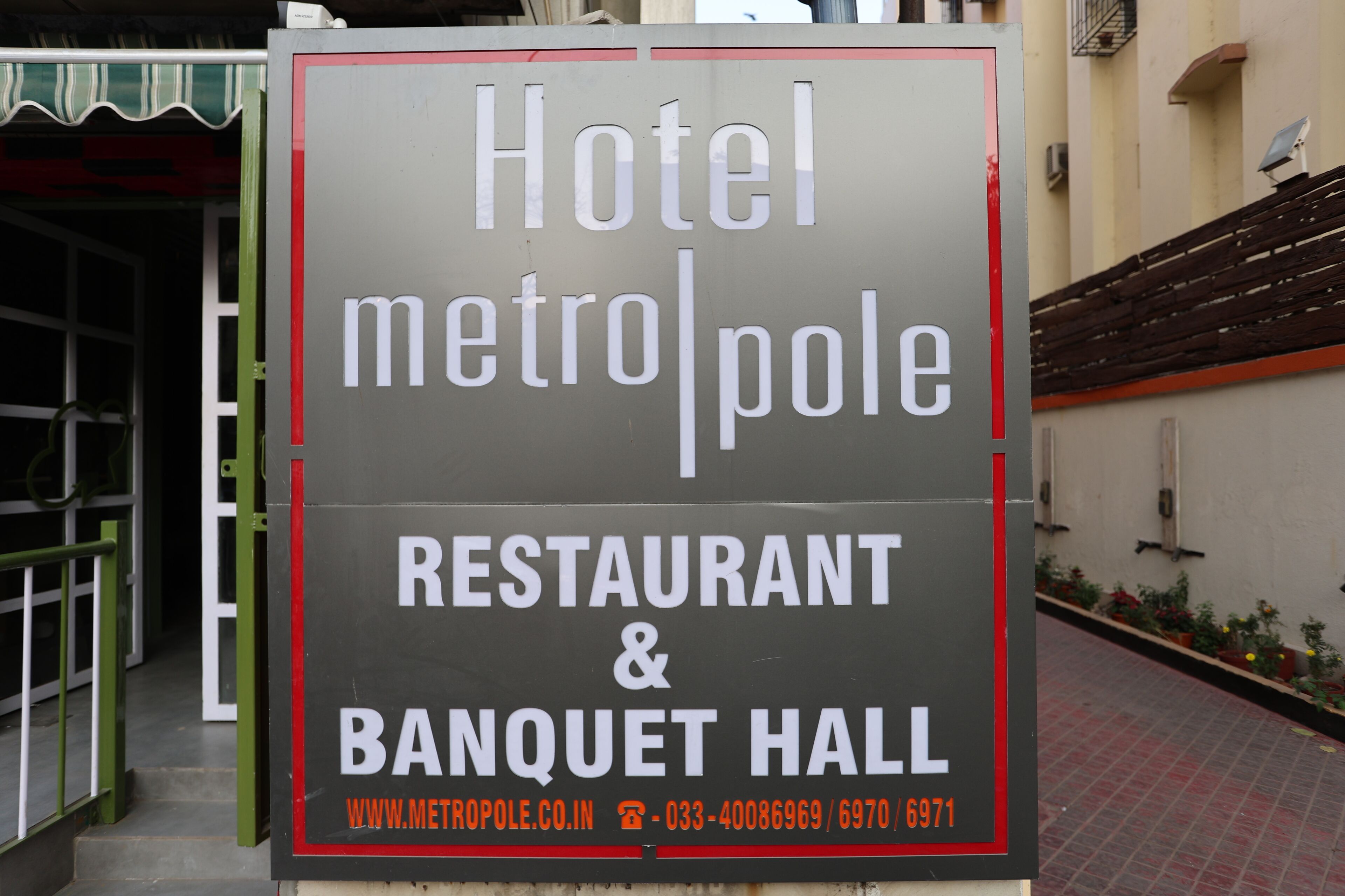 A sign for Hotel MetroPole, Restaurant & Banquet Hall, including contact information and website.
