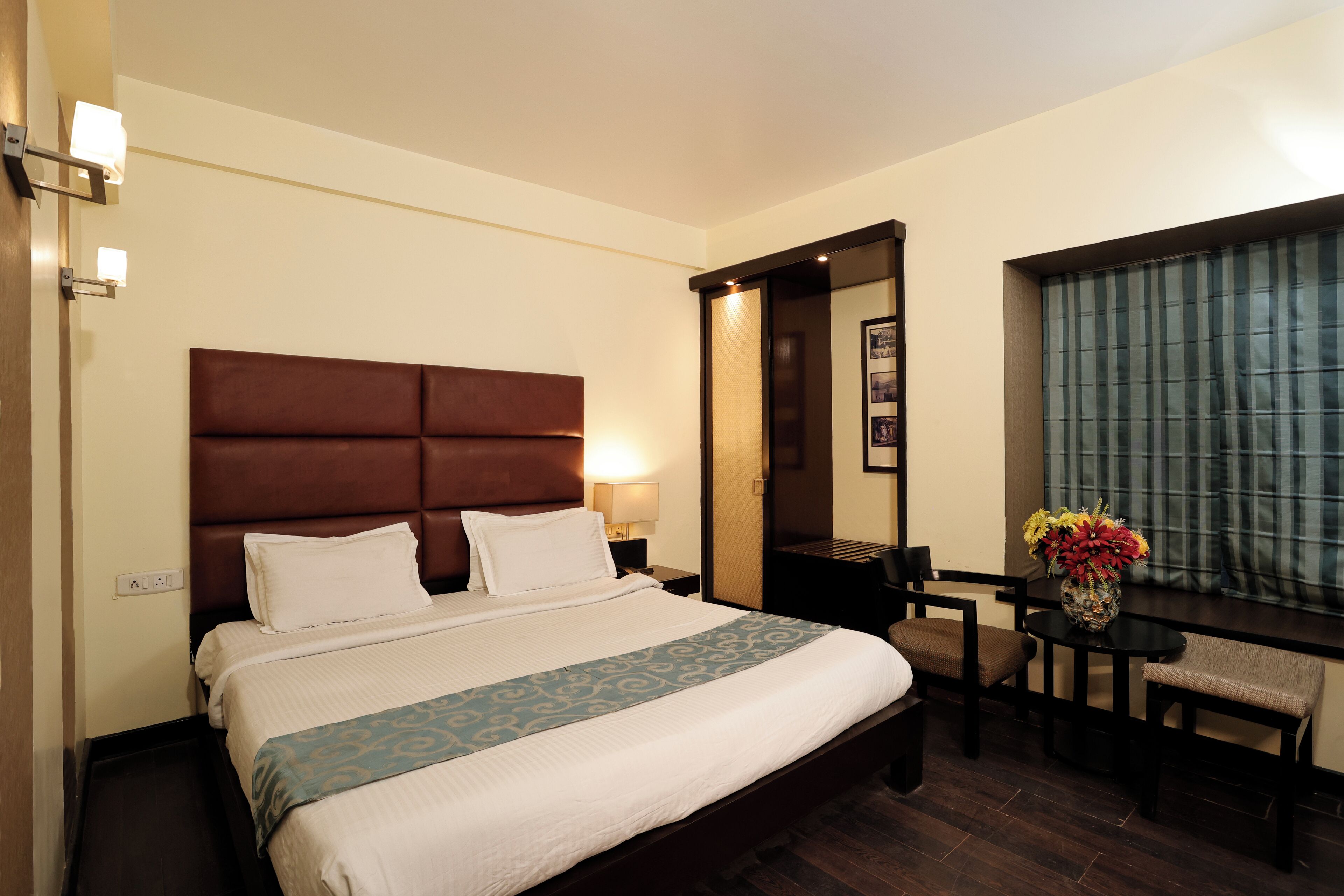 Una habitación de hotel con una cama grande, mesitas de noche, un escritorio y una silla.