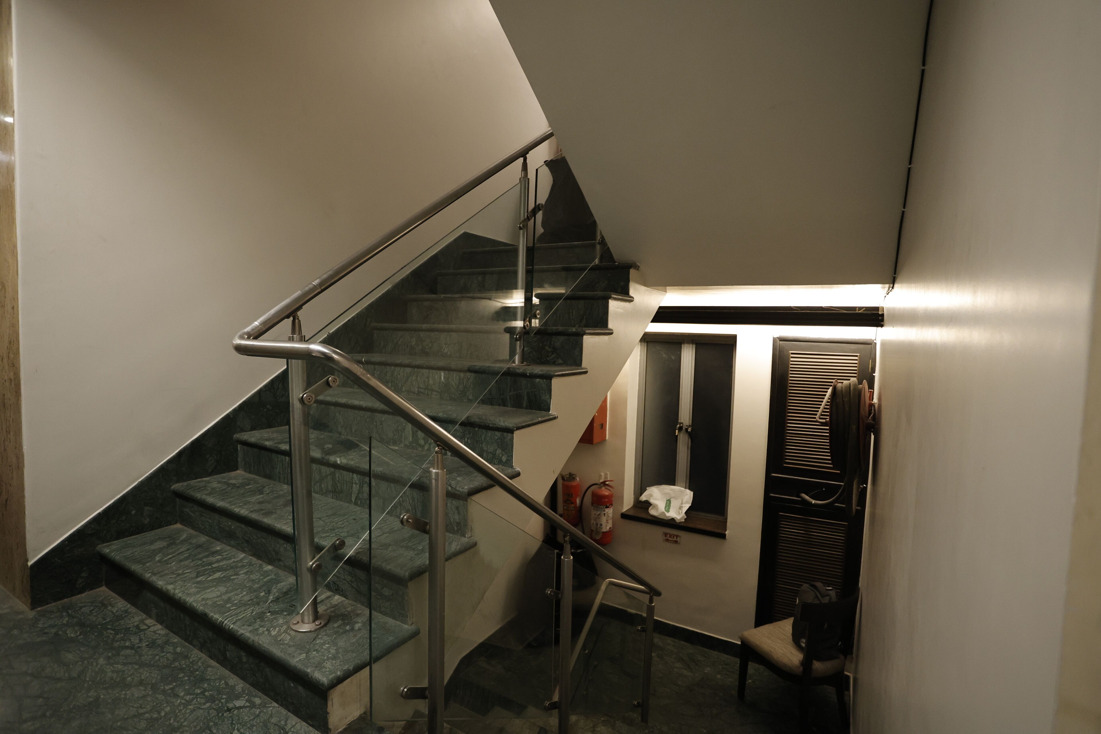 A staircase with metal railings, a fire extinguisher, and a chair near a door.