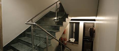 A staircase with metal railings, a fire extinguisher, and a chair near a door.