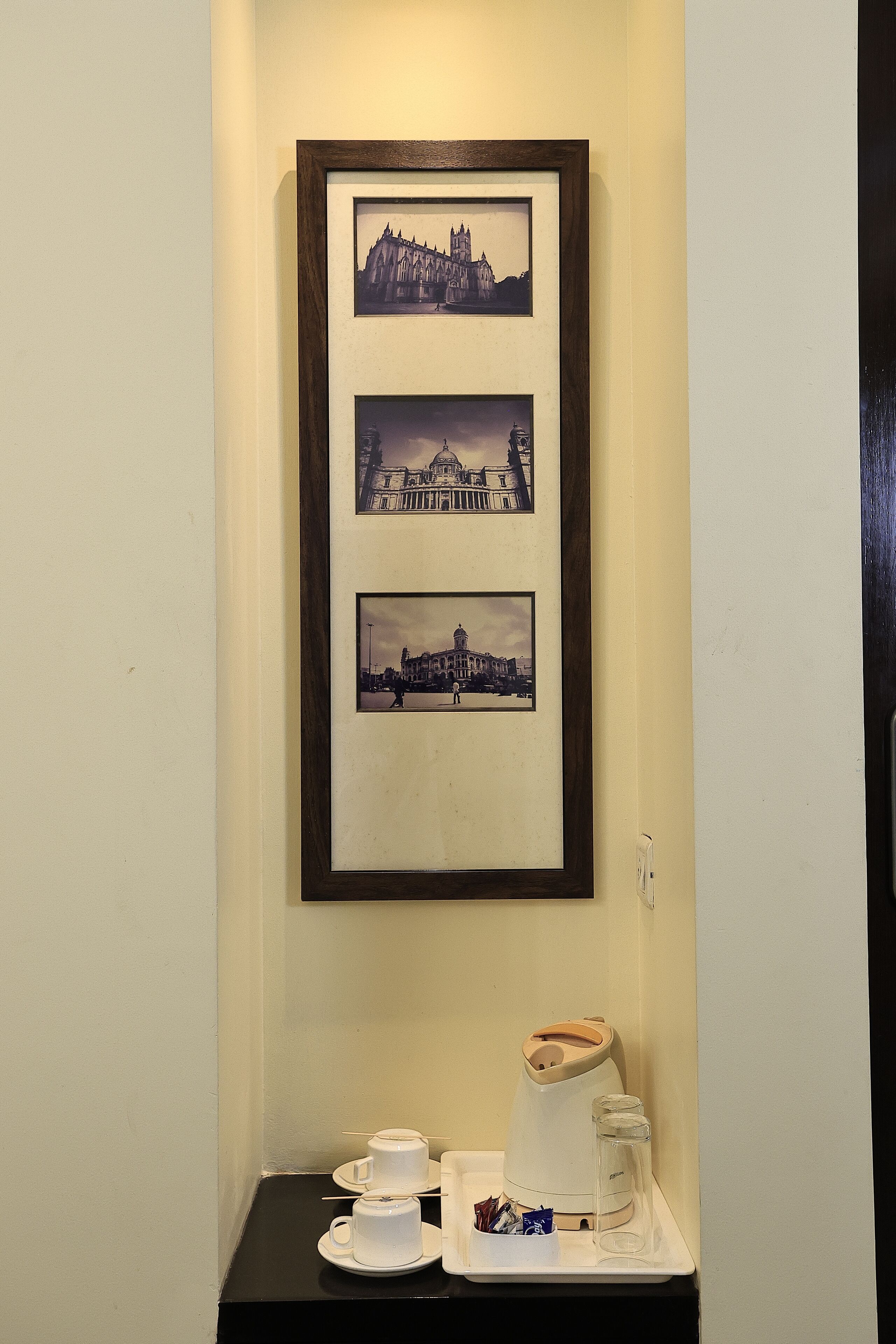 A framed photograph of a historic building, a coffee maker, and cups on a tray.