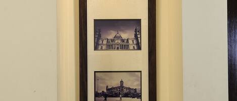 Una fotografía enmarco de un edificio histórico, una cafetera y tazas sobre una bandeja.