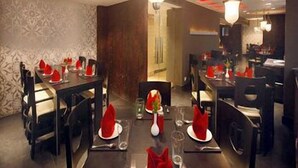 Interior de restaurante con mesas dispuestas para comer, con servilletas rojas y copas de cristal.