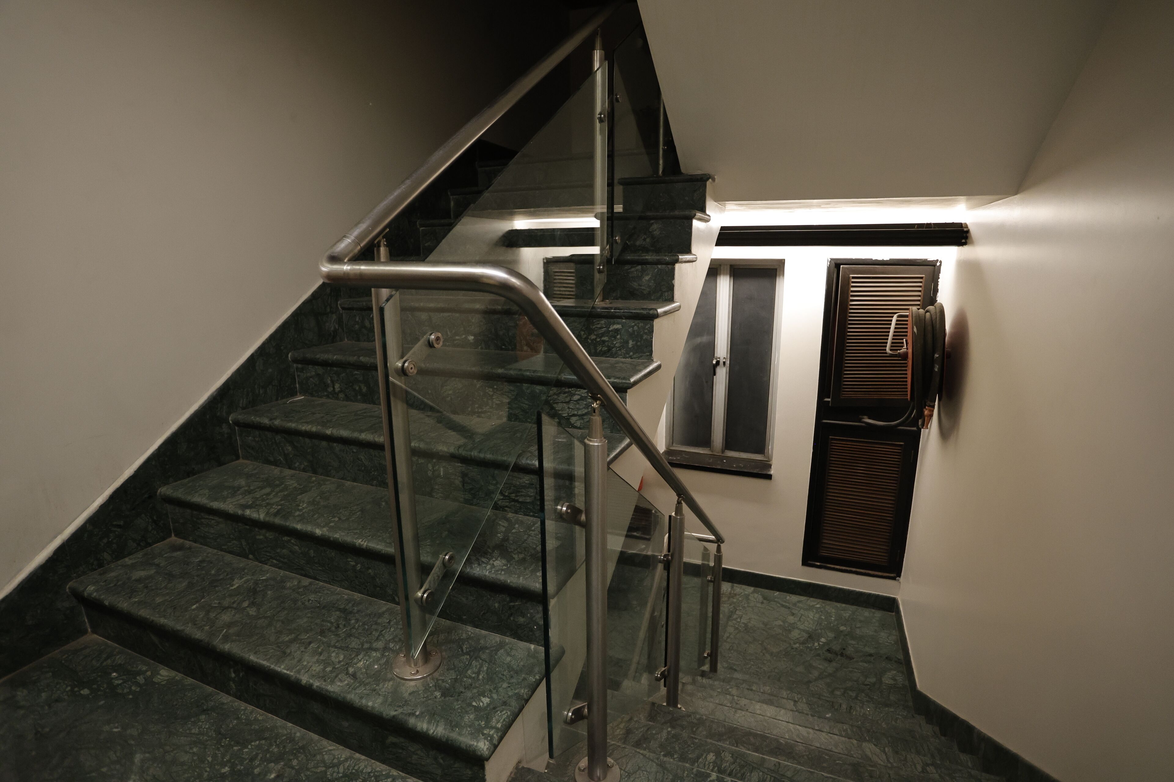 Una escalera con barandillas de vidrio y un respiradero en la pared.