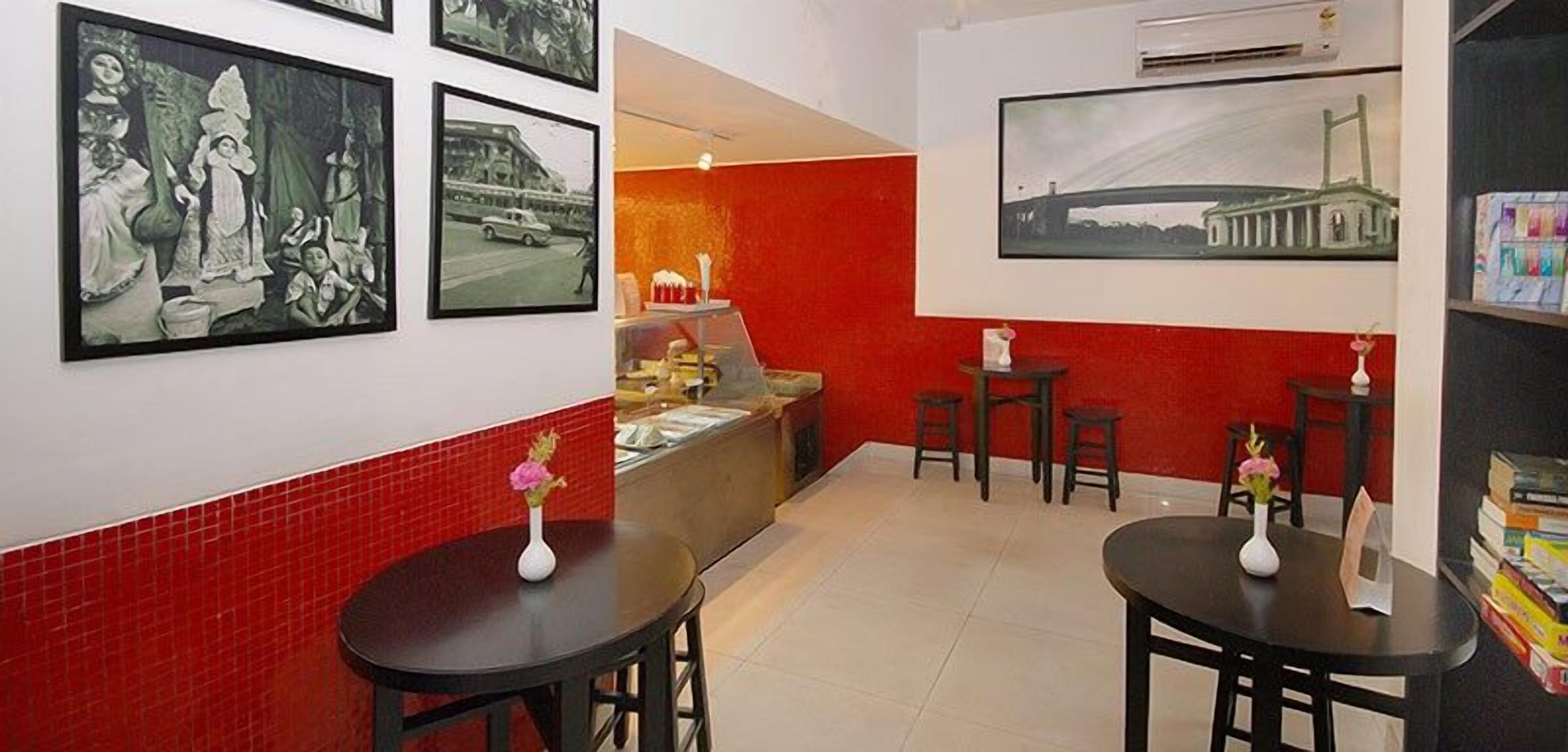 A hotel lobby with red and white walls, a reception desk, and several tables with vases.