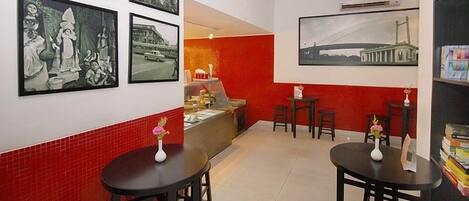 A hotel lobby with red and white walls, a reception desk, and several tables with vases.
