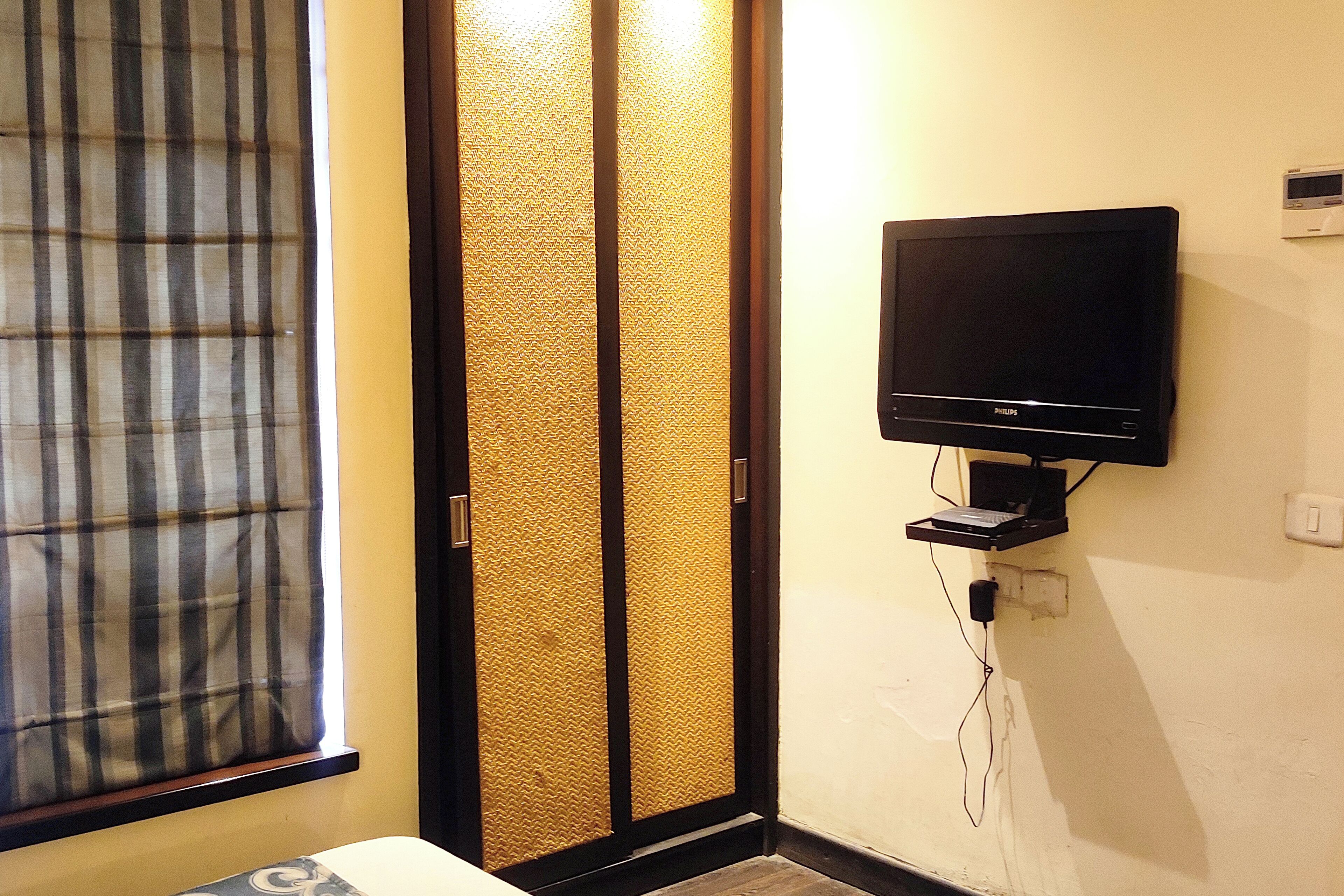 A room with a sliding shoji screen door, a mounted television on the wall, and a power outlet.
