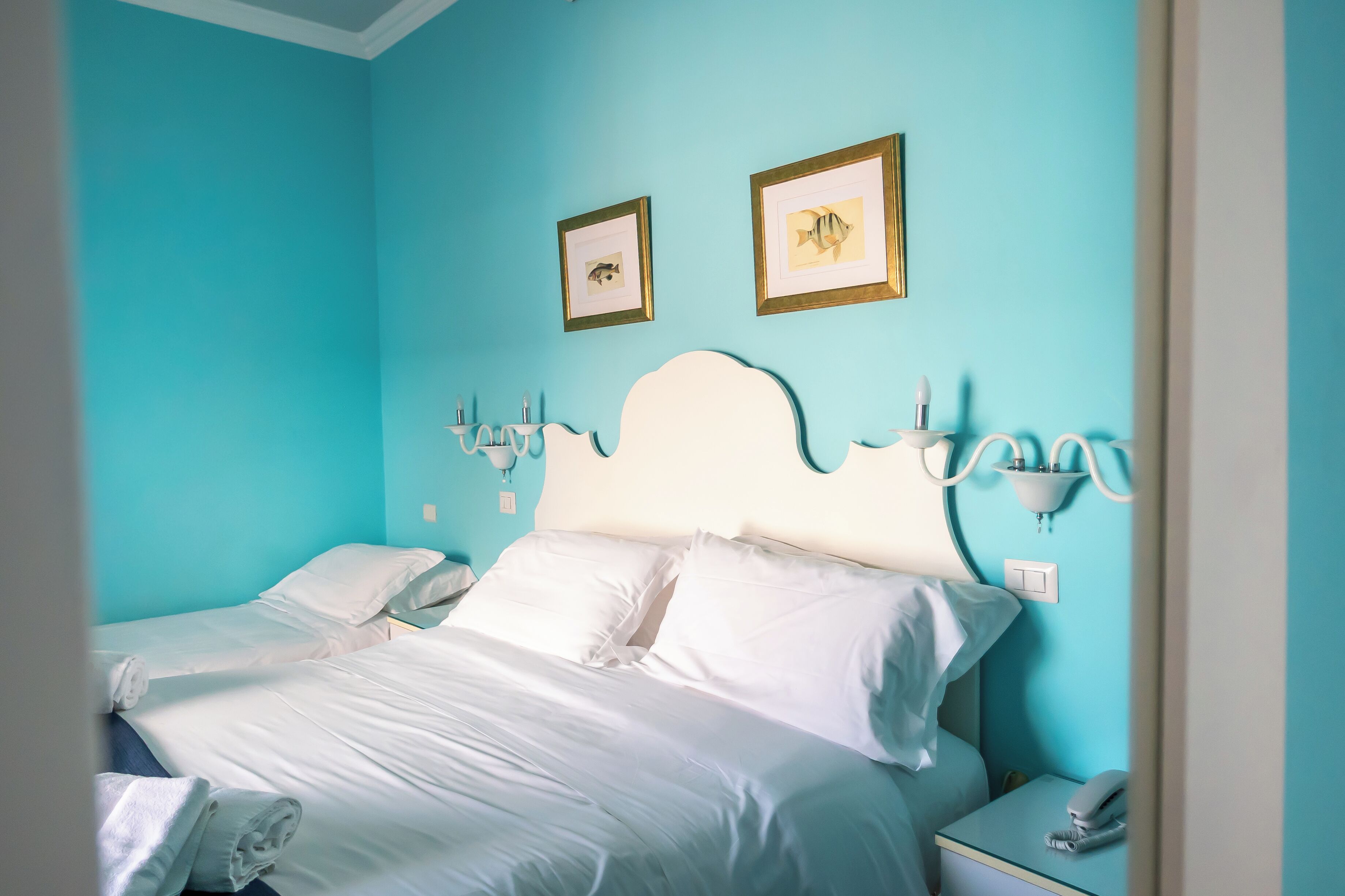 A hotel room with a bed, two bedside tables, a nightstand, and wall-mounted lamps.