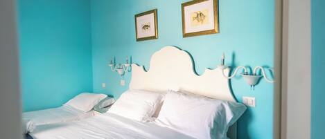 A hotel room with a bed, two bedside tables, a nightstand, and wall-mounted lamps.