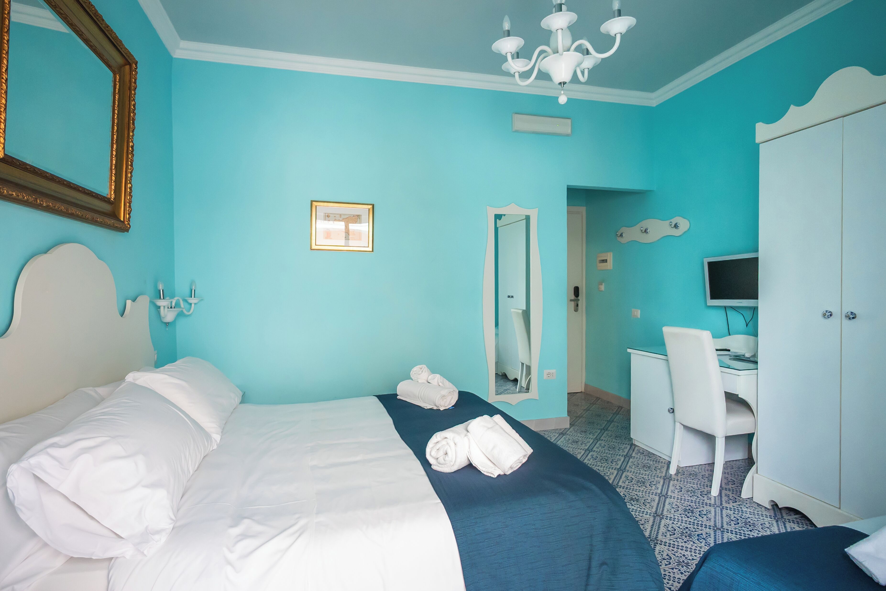A hotel room with a bed, a desk, a chair, and a wardrobe.