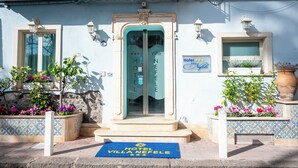 Entrada de un hotel con una puerta azul, un cartel que dice "Villa Nepehe Hotel" y un felpudo azul con el nombre del hotel.