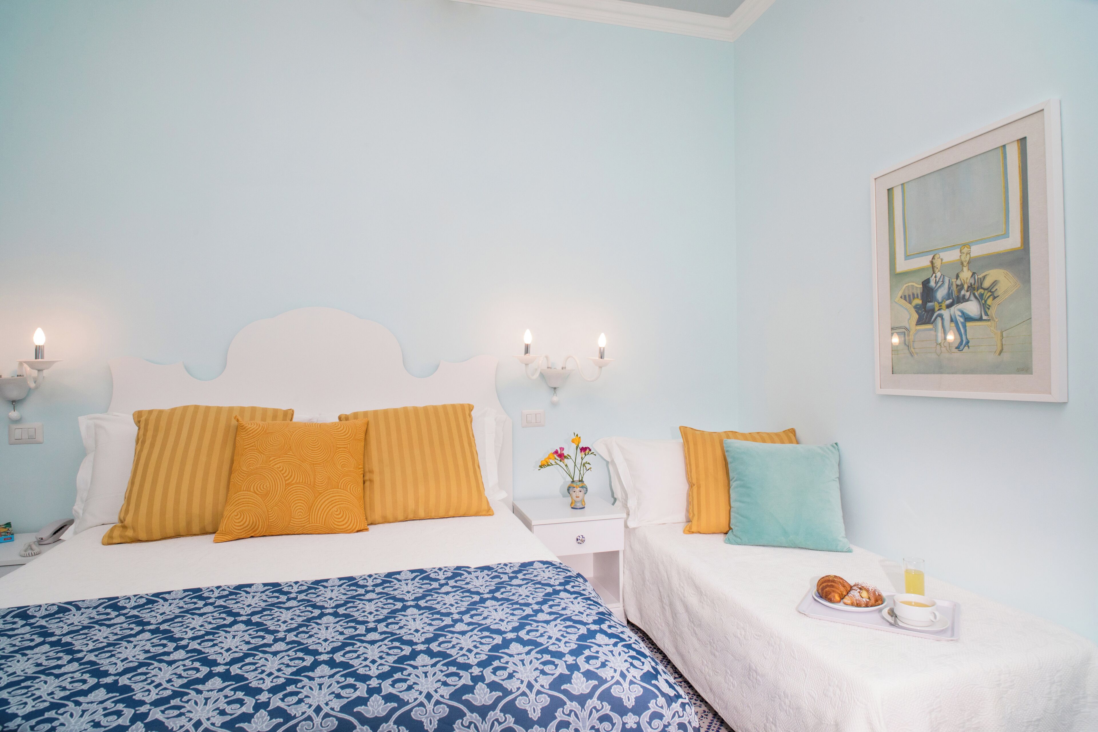 A bedroom with a bed, bedside tables, and a painting on the wall.
