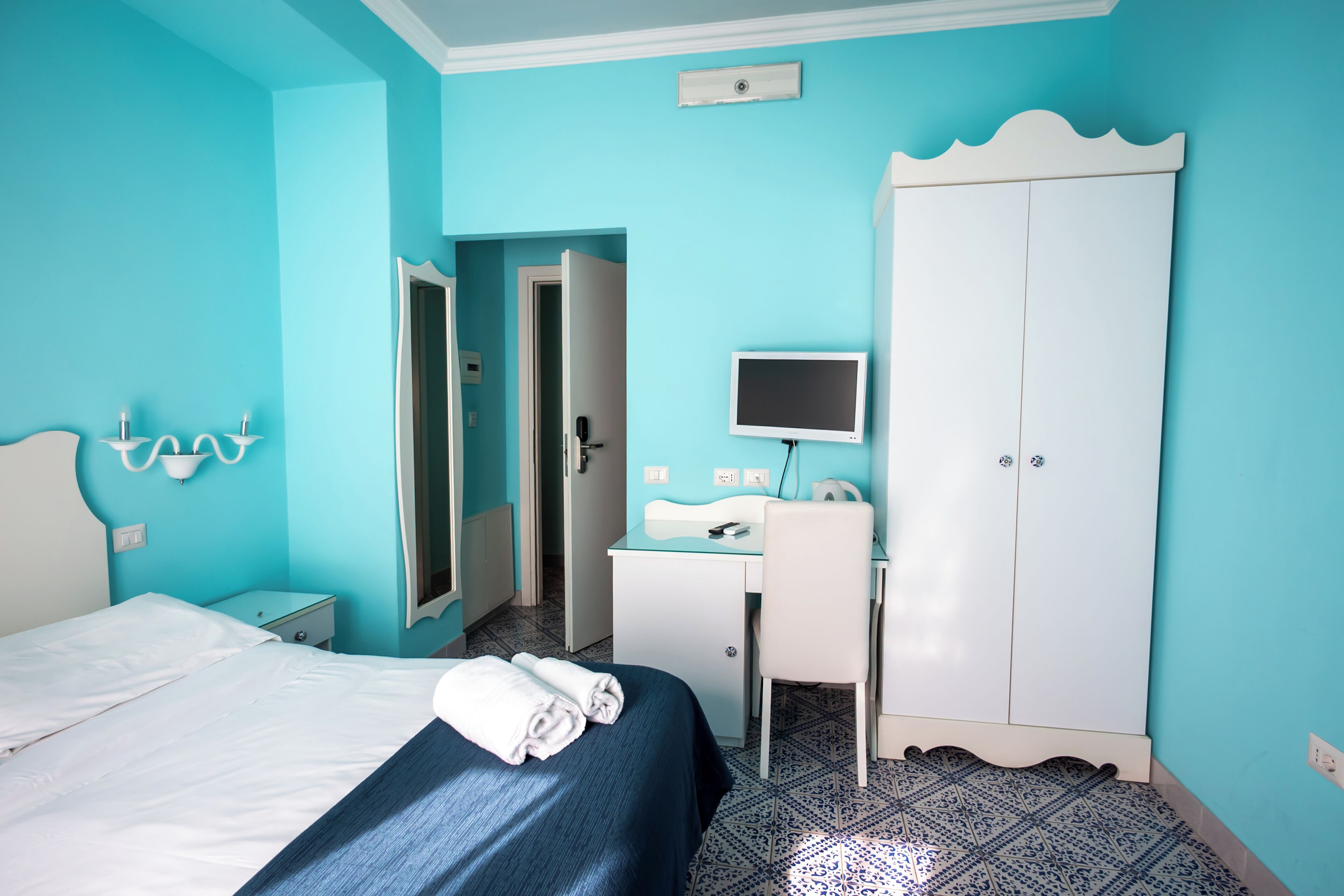 A room with a bed, a desk, a wardrobe, and a television.