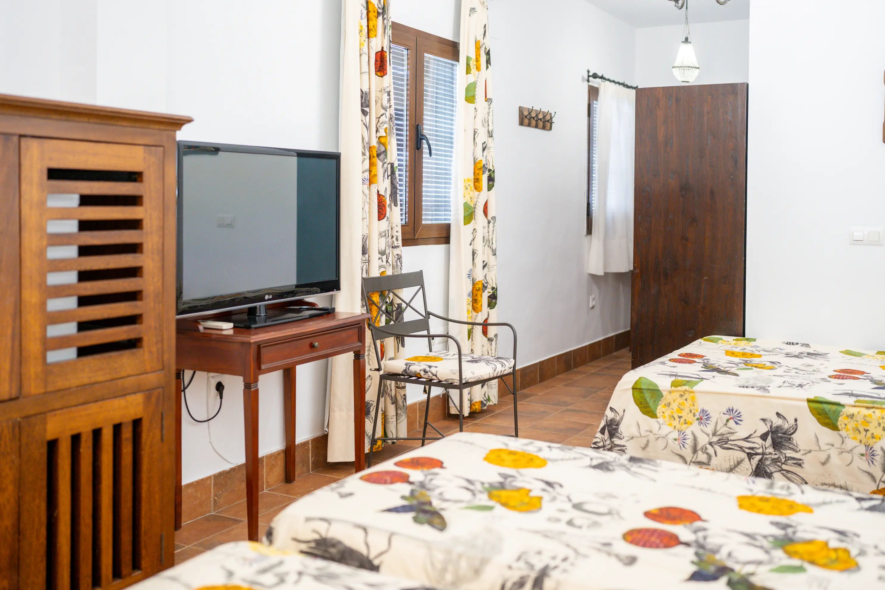 Un dormitorio con cama, escritorio, silla, televisor y armario.