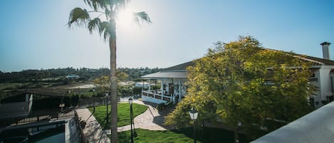 A building with a covered patio, a pathway, and a pool.
