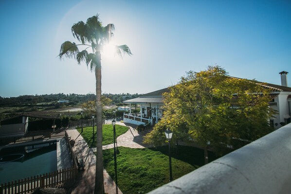 A building with a covered patio, a pathway, and a pool.