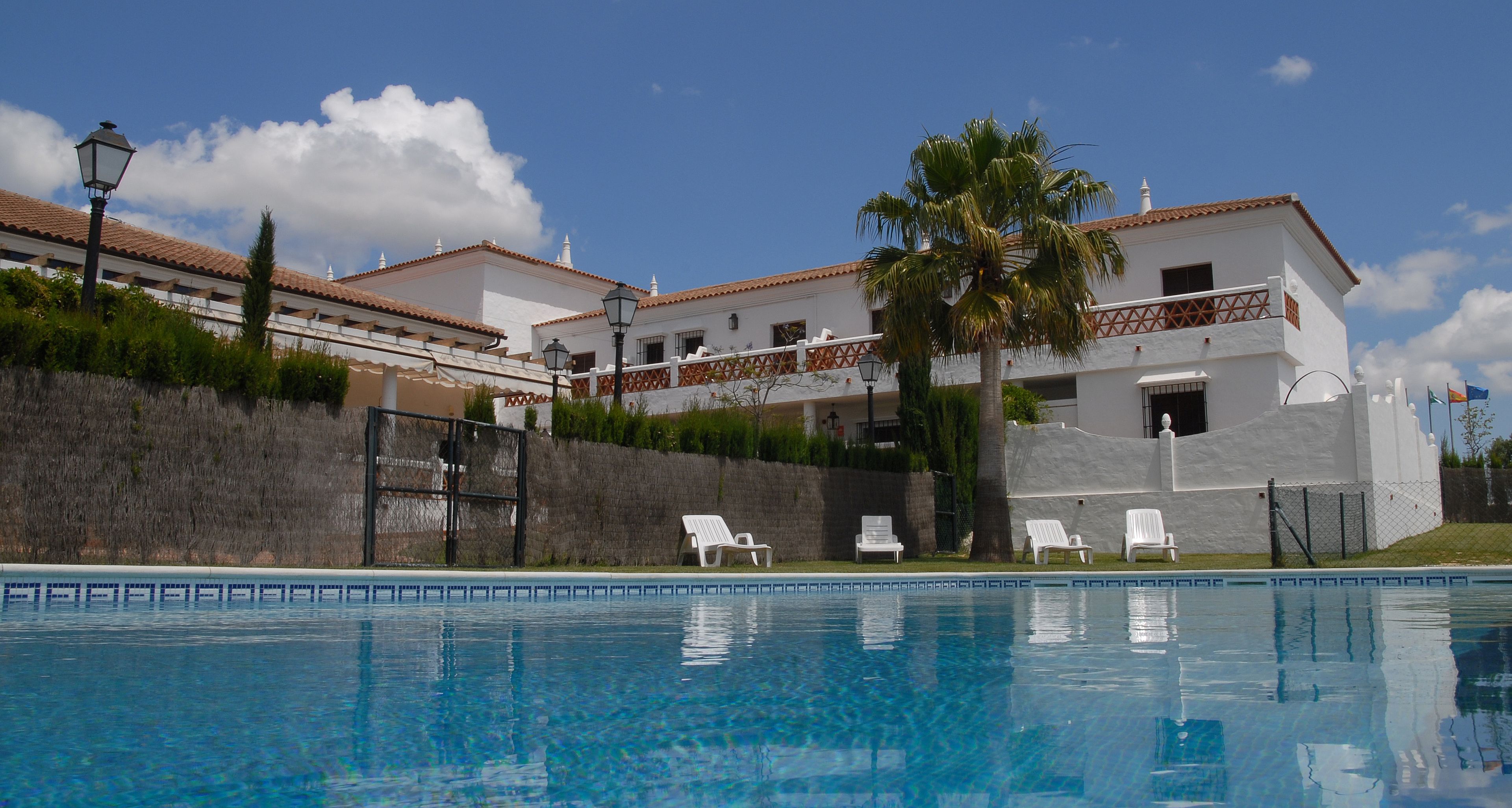 Una piscina al aire libre, sombrillas, tumbonas