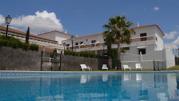Una piscina al aire libre, sombrillas, tumbonas