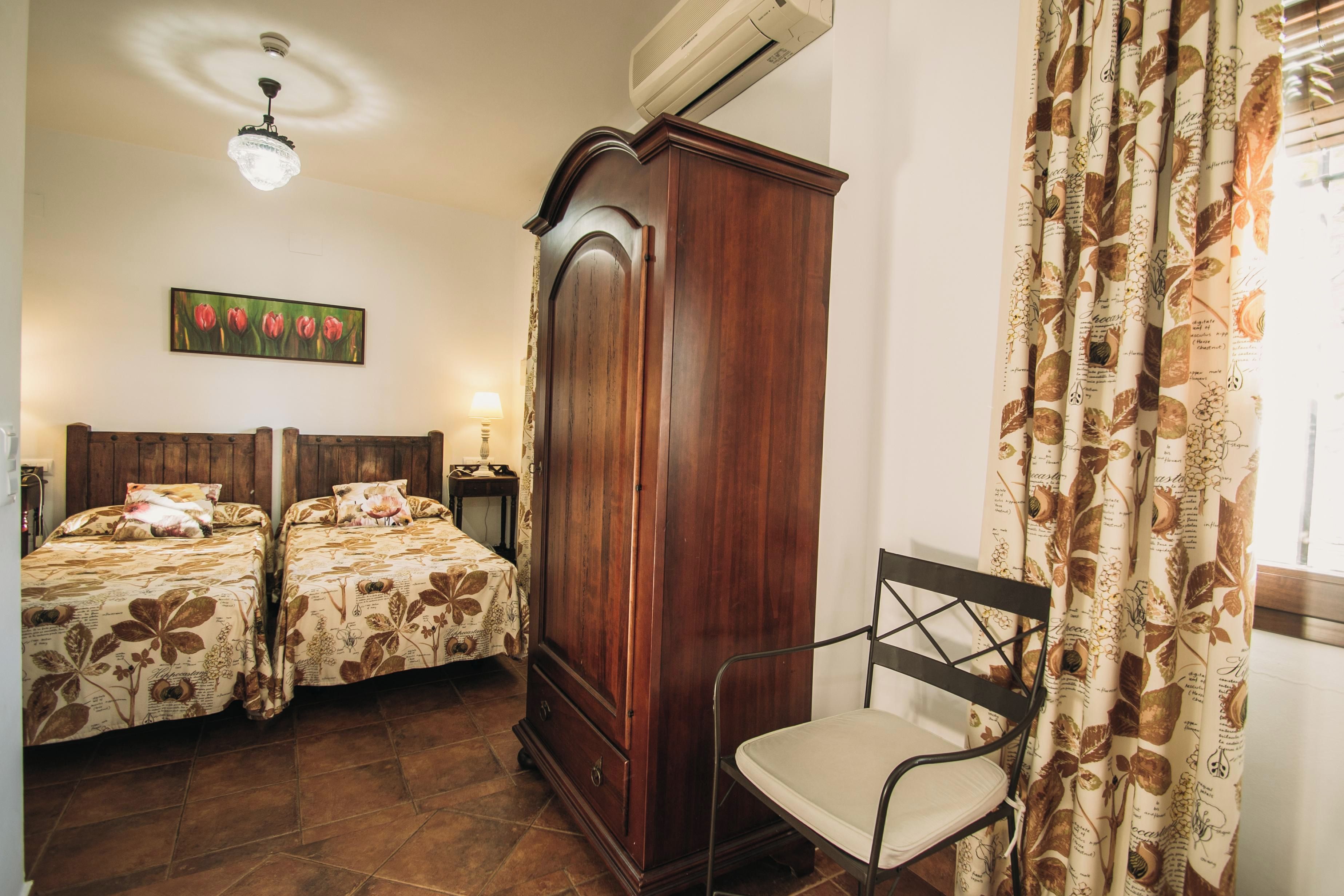 Une chambre avec deux lits, une armoire, une chaise et un tableau au mur.