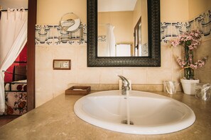 A bathroom with a white sink, a mirror with a decorative frame, and a shower curtain.