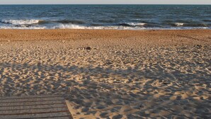 A sandy beach with a wooden walkway leading to the water. - Hotel Valsequillo (Lepe)
