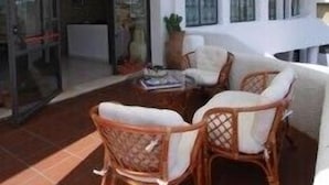A covered outdoor seating area with wicker chairs and a table, a large umbrella, and a glass door leading to an interior space. - Residenza de Leonardis (Alberobello)