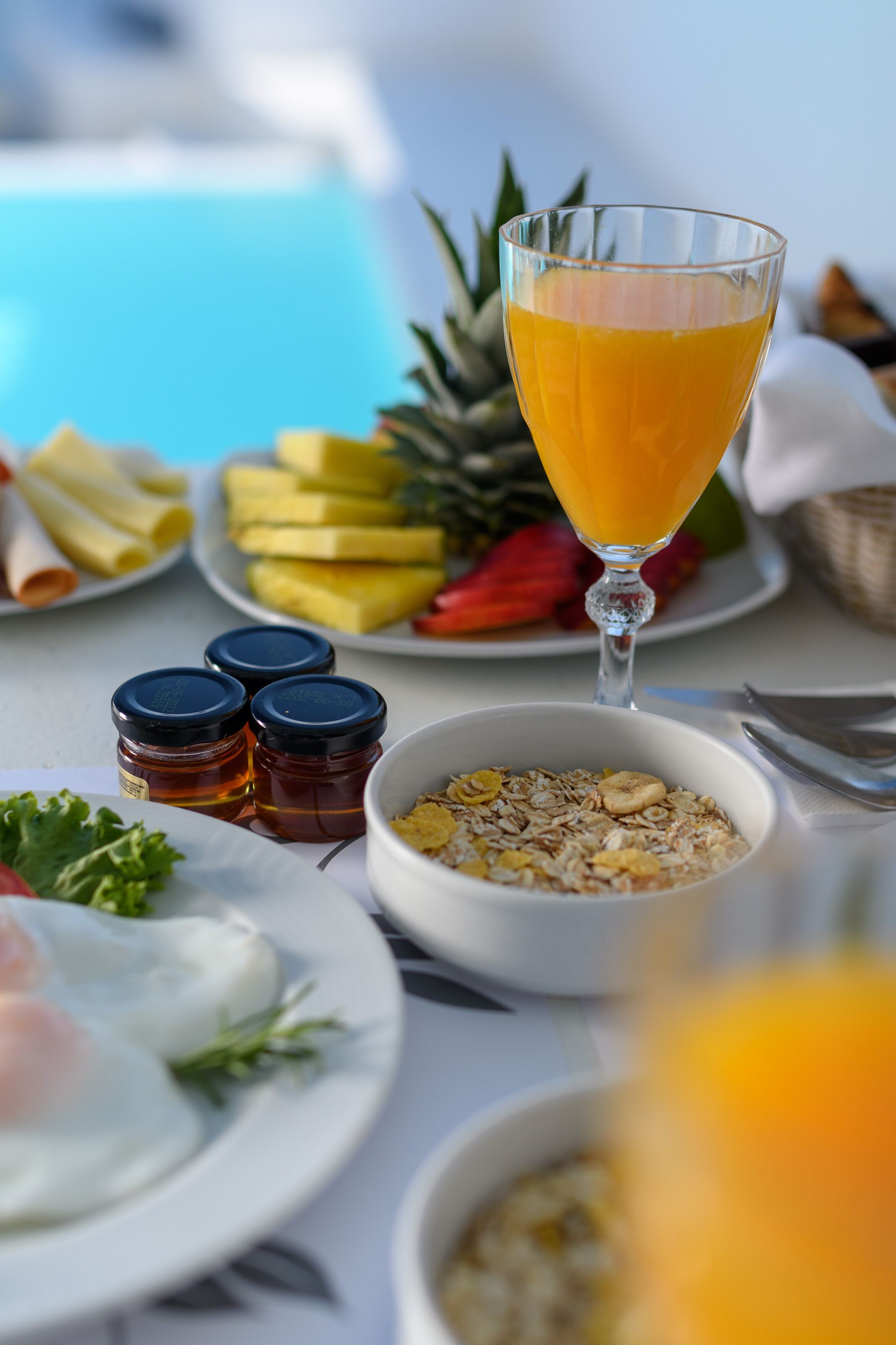 A breakfast setting with plates of food, a glass of orange juice, and condiments.
